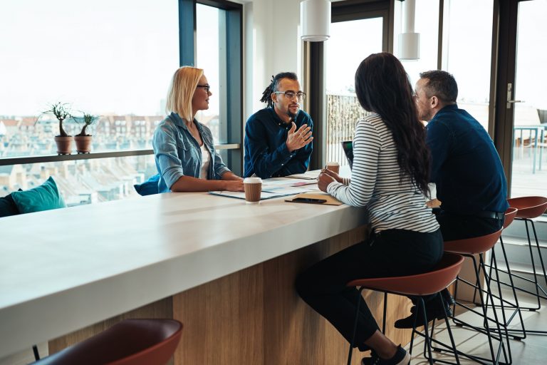 Smiling young African American office worker talking business with colleagues